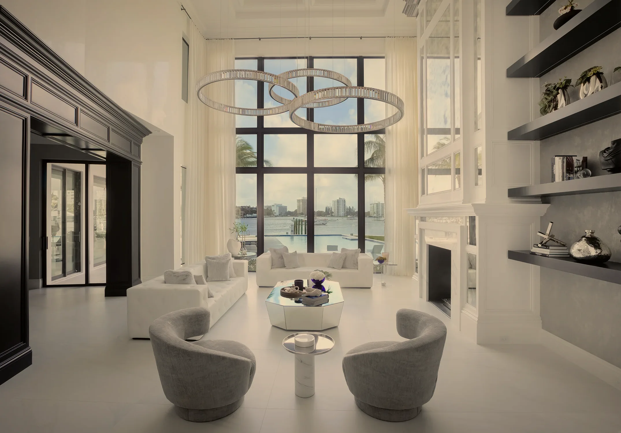 Double-height living room with crystal ring chandeliers and floor-to-ceiling windows overlooking the waterfront